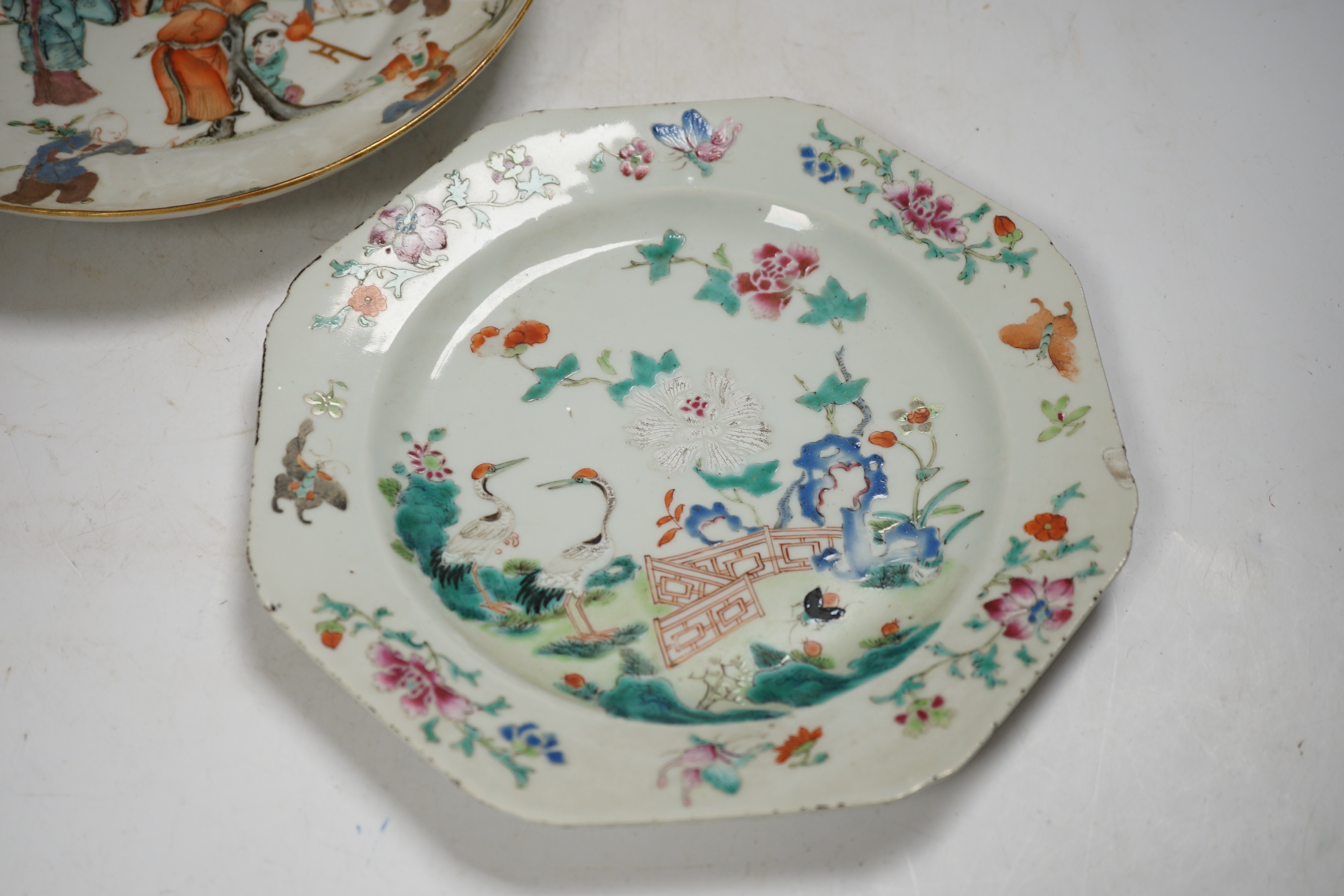 A Chinese famille rose ‘boys’ saucer dish, Tongzhi seal mark and probably of the period (1862-1874) and an 18th century Chinese famille rose octagonal ‘cranes’ plate, dish 25cm diameter